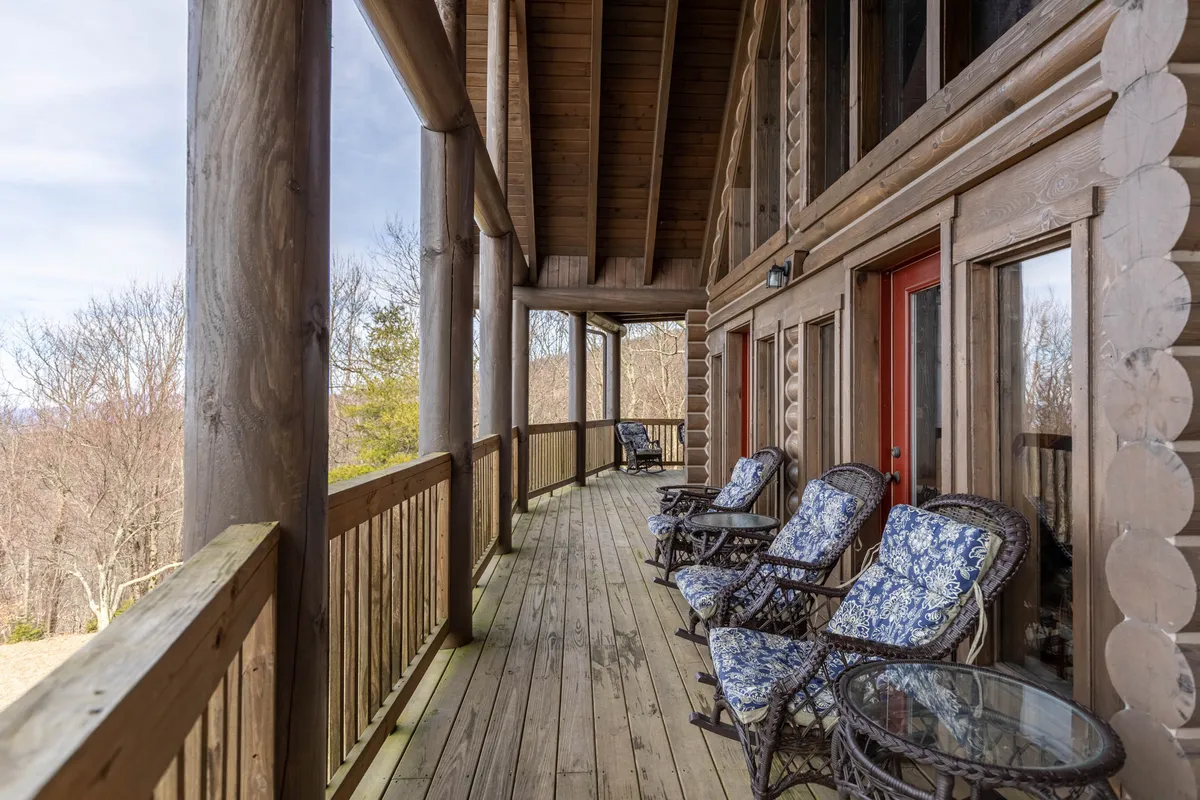 A peaceful exterior view of the log cabin's porch, featuring wooden rocking chairs and sturdy railings. Surrounded by natural mountain scenery, the porch invites guests to relax and enjoy the tranquil outdoor environment—perfect for those traveling with dogs who want easy access to the outdoors.